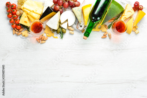 Wine, cheese and grapes on a white wooden background. Italian cuisine. Top view. Free space for your text.