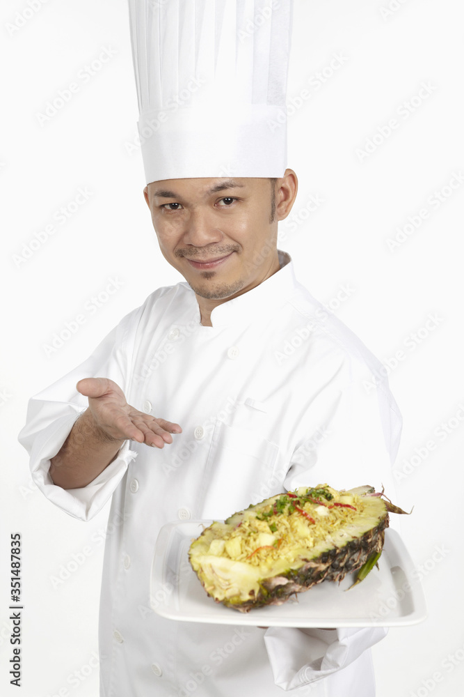 Asian chef with a plate of Thai pineapple fried rice Asian chef with a plate of Thai pineapple fried rice