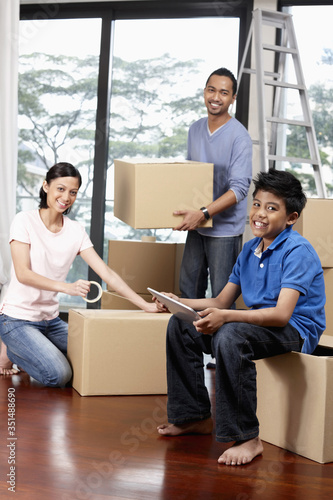 Boy using digital tablet, man and woman packing in the background © ImageHit