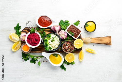 Fototapeta Naklejka Na Ścianę i Meble -  Set of sauces and spices on white wooden background. Top view.
