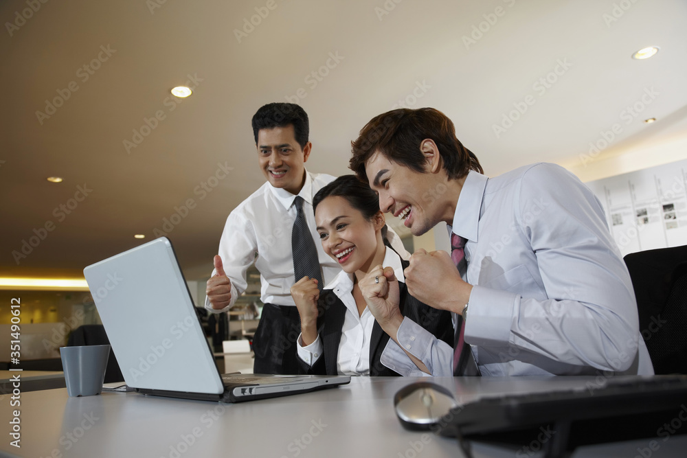 Business people cheering while looking at laptop on table Business people cheering while looking at laptop on table