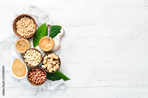 Peanut butter and nuts on a white wooden background. Free space for your text.