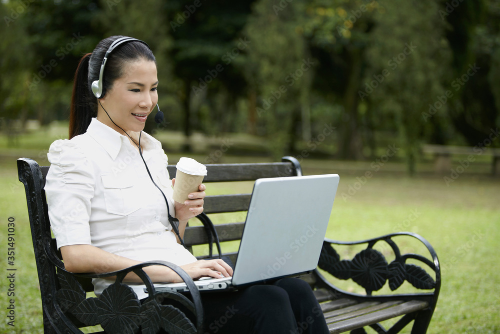 Mid adult businesswoman having a conference call while eating Mid adult businesswoman having a conference call while eating