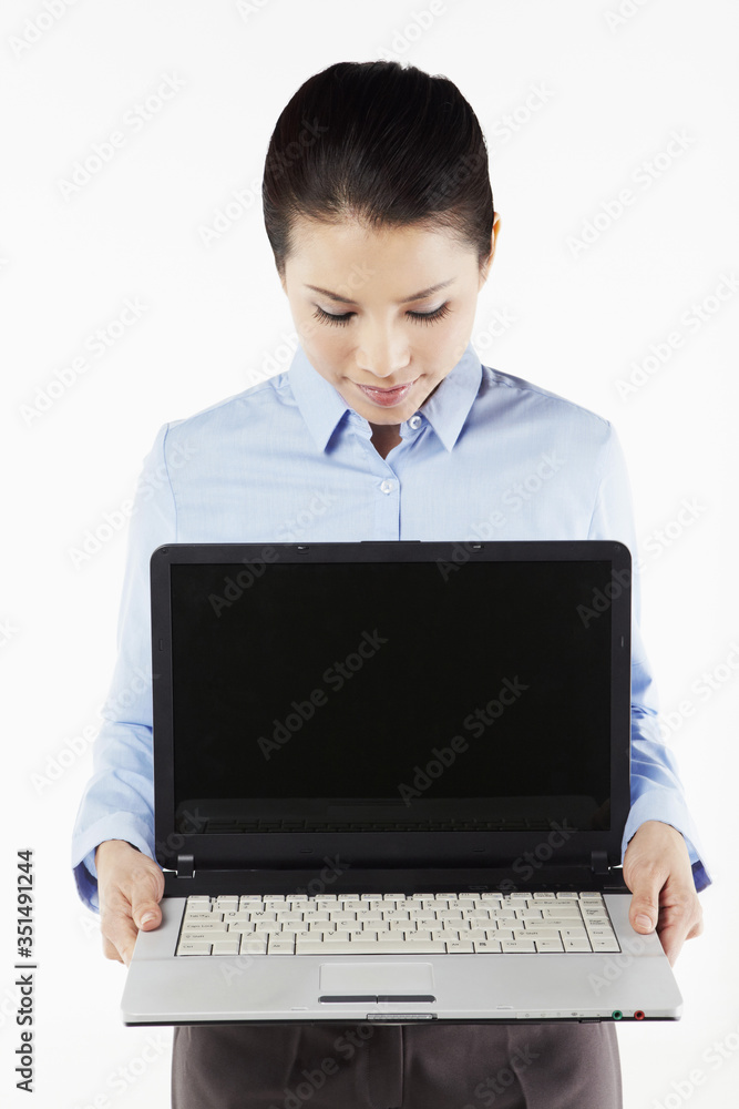 Mid adult businesswoman holding laptop Mid adult businesswoman holding laptop