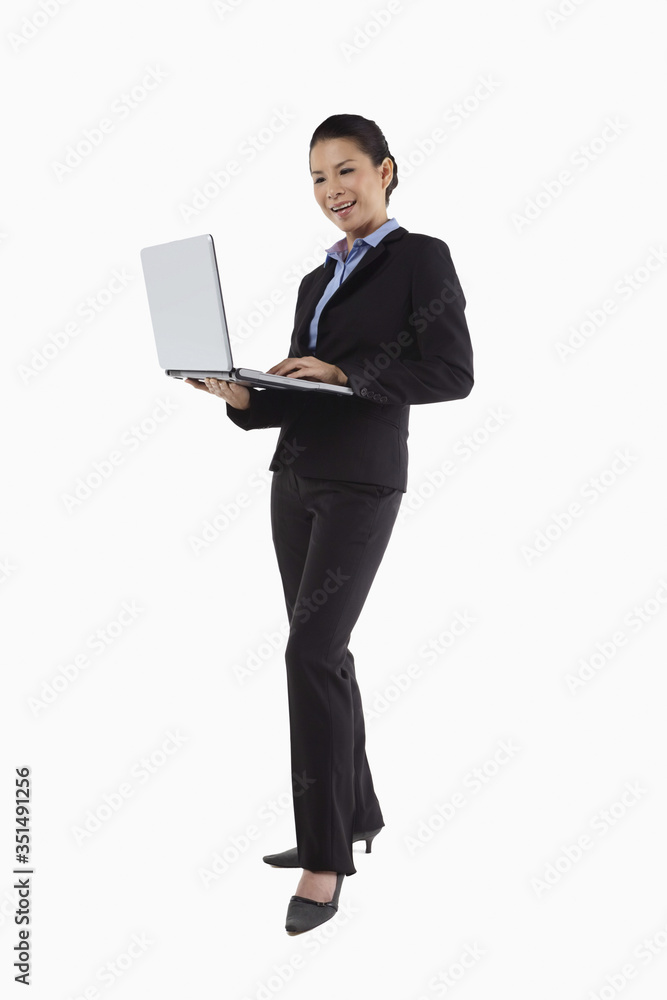Mid adult businesswoman using laptop while standing Mid adult businesswoman using laptop while standing