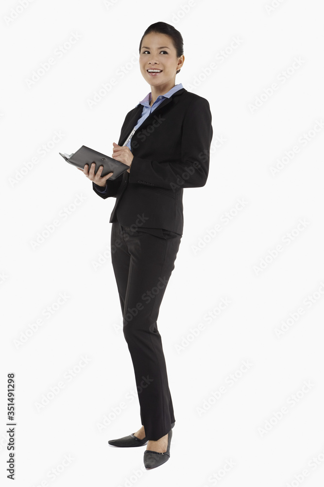 Mid adult businesswoman writing notes in organizer Mid adult businesswoman writing notes in organizer