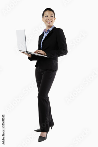 Mid adult businesswoman using laptop while standing