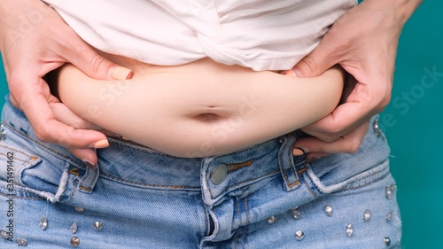 Fat woman, Obese woman hand holding excessive belly fat isolated on green background, Overweight fatty belly of woman, Woman diet lifestyle concept to reduce belly and shape up healthy stomach muscle