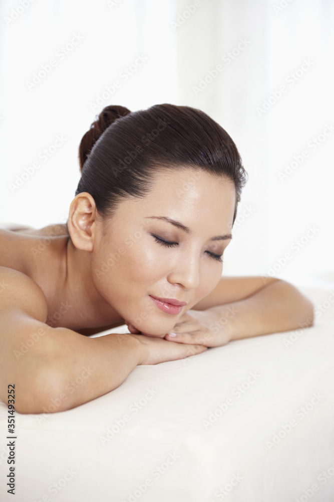 Woman lying forward on massage table with her eyes closed Woman lying forward on massage table with her eyes closed