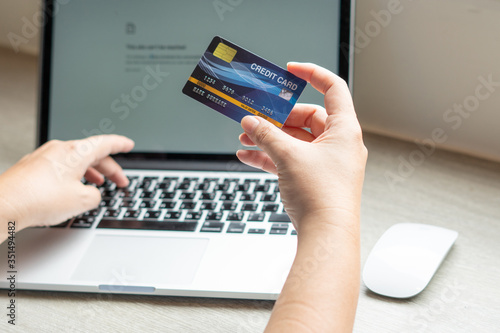 Business woman hand hold credit card to shopping internet online bill on computer, Debit saving purchase buy on table background. Shopaholic people retail pay sale money, bank terminal account concept