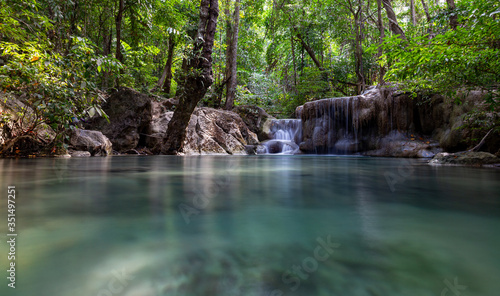 Beautiful small waterfall in tropical forest with still emerald green water in Erawan National Parik