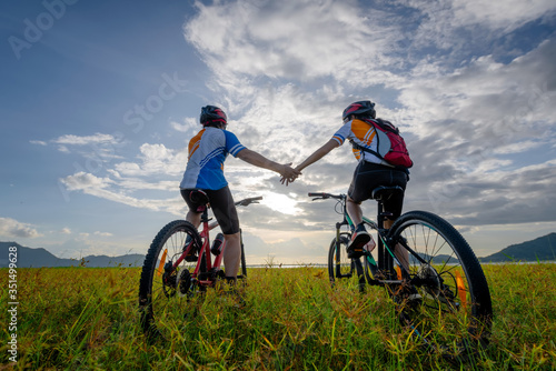 family couple lover enjoy the life of riding biking on the fresh field meadow grass, cheerfully life holding hand together on outdoors activity