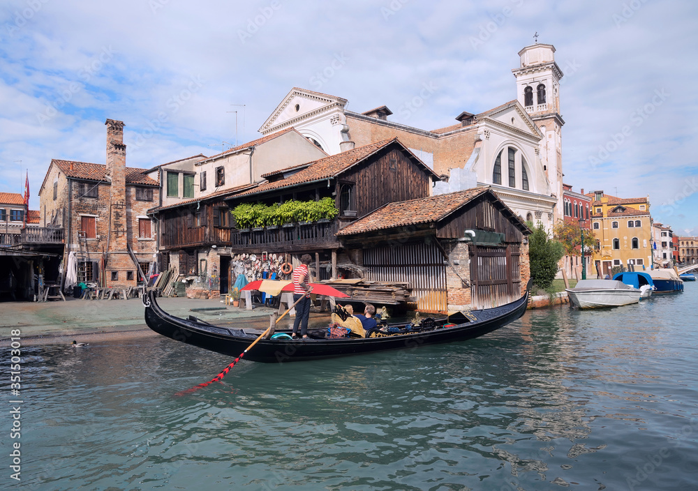 Obraz premium Gondola with tourist near Gondolas Repair Yard in Venice.