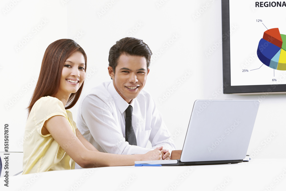 Cheerful businessman and businesswoman working on laptop together