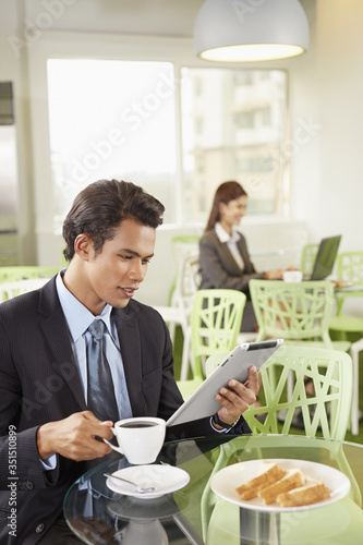 Businessman using a digital tablet while having a drink