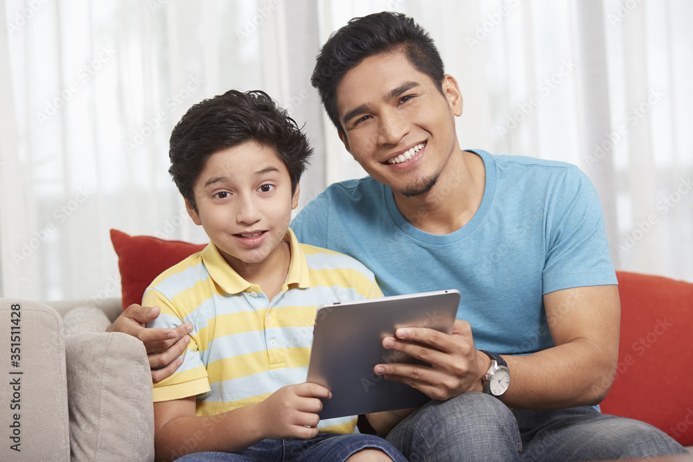Father and son using a digital tablet together Father and son using a digital tablet together