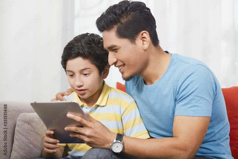 Father and son using a digital tablet together Father and son using a digital tablet together