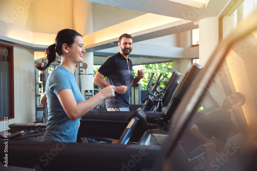 Couple exercise together in gym. Man and woman working out in fitness club. Healthy lifestyle, training in gym.