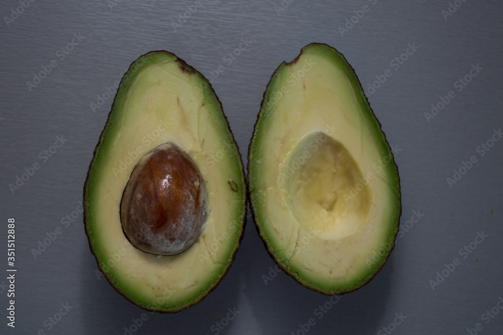 avocado cut in half on wooden surface