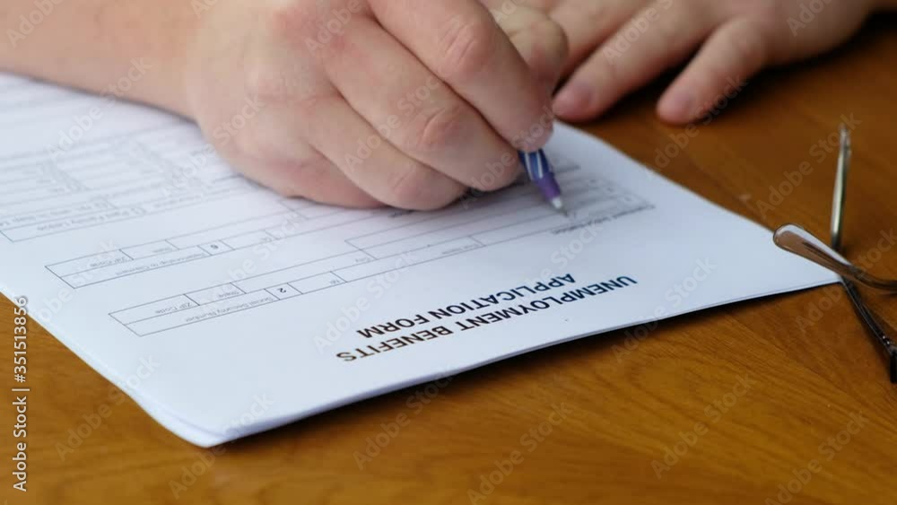 Somebody filling an unemployment benefits application form. Close up Somebody filling an unemployment benefits application form. Close up