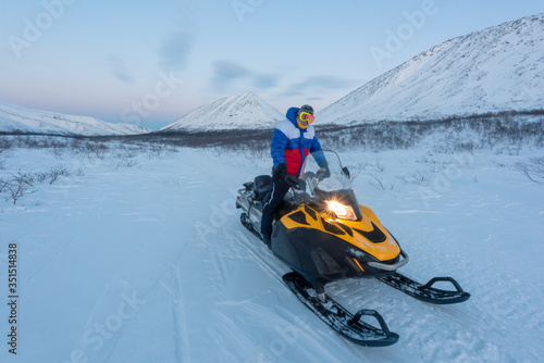Happy smiling man driving snowmobile in Finnish Lapland