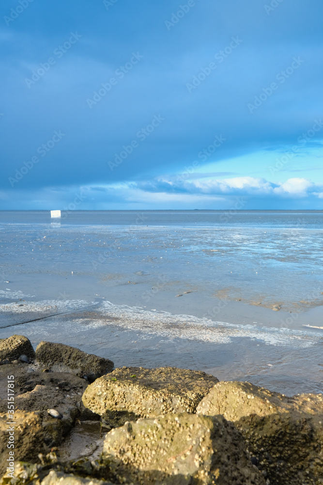 A container ship has lost a cargo at sea, off the coast of Friesland, the Netherlands. A freezer floats at sea, environmental pollution, rocks in foreground. Unesco world heritage A container ship has lost a cargo at sea, off the coast of Friesland, the Netherlands. A freezer floats at sea, environmental pollution, rocks in foreground. Unesco world heritage