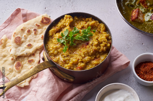 Indian red lentil curry soup dal with rice naan. Vegan indian dish on concrete background