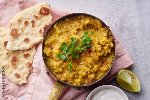 Indian red lentil curry soup dal with rice naan. Vegan indian dish on concrete background