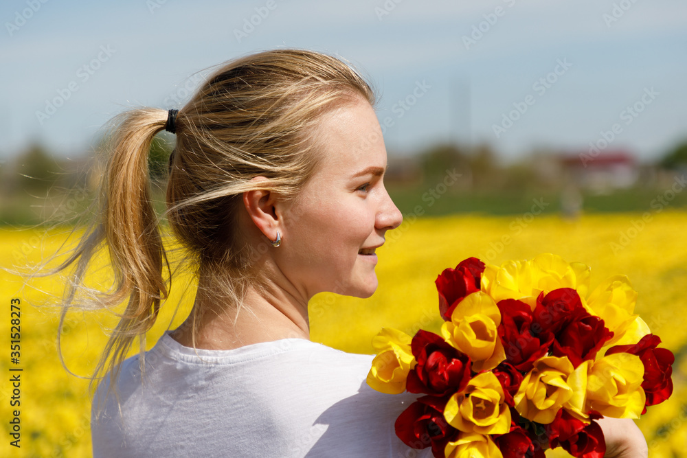 Fototapeta premium The young woman with tulips in the tulip field