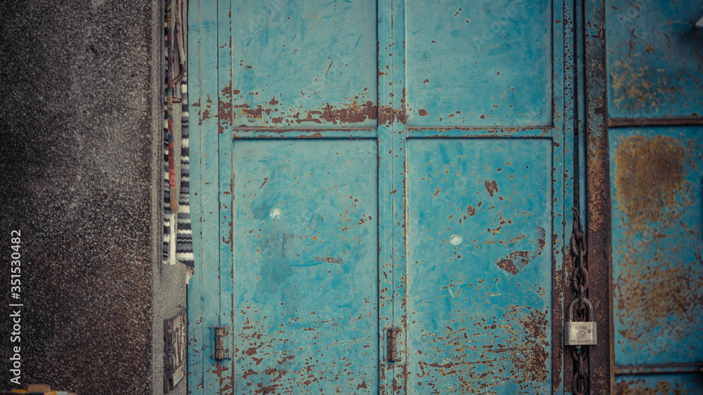 blue rusted door with rusty chains with padlock