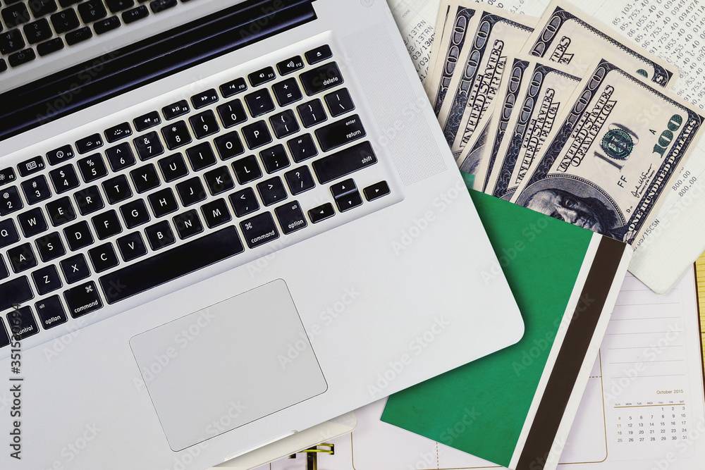 Top view of laptop with book bank and banknote on statement paper background.Finance concept. Top view of laptop with book bank and banknote on statement paper background.Finance concept.