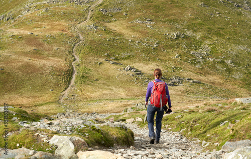 Photo A hiker descending the rocky path from Brim Fell and walking towards Dow Crag on a sunny Day in the Lake District