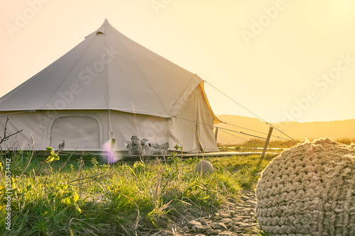 path to a glamping tent in the middle of a green field in the sunset rays. Camping and outdoor concept.