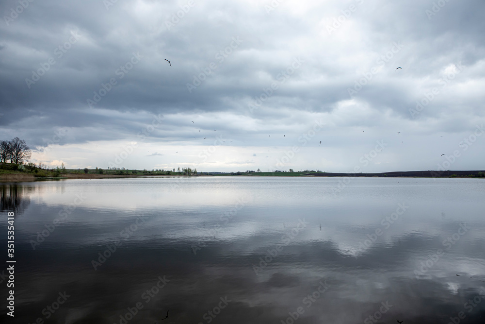 dark rain clouds hang low in the sky and reflected in the lake