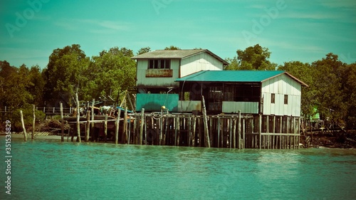 House with wooden pillars on the water sea © Oz Rao