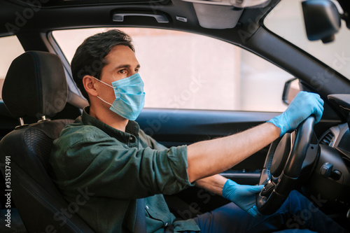 a man driving a car puts on a medical mask during an epidemic, protection from the virus
