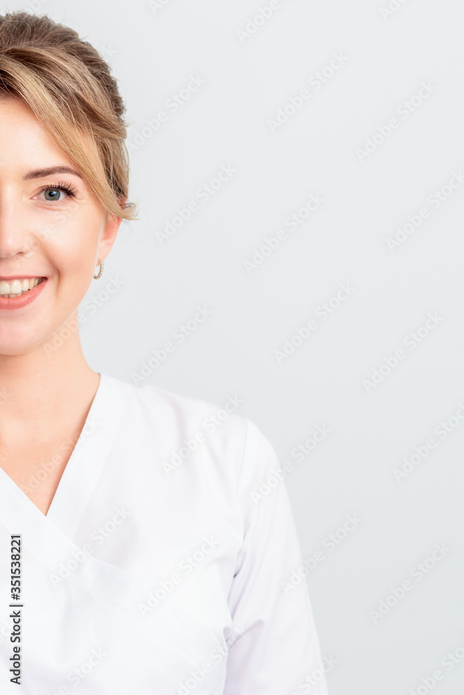 Half face portrait of beautiful doctor or intern or cosmetologist in white robe stands smiling at the camera, isolated on white background. Half face portrait of beautiful doctor or intern or cosmetologist in white robe stands smiling at the camera, isolated on white background.