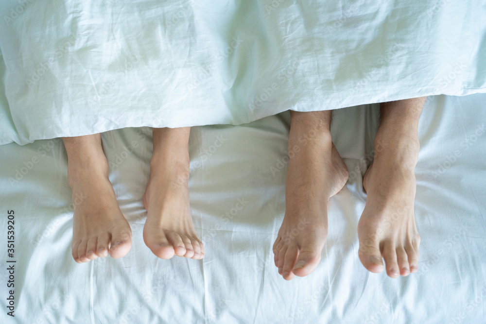 Couple in bed making love. male and female legs top view. White linens Couple in bed making love. male and female legs top view. White linens