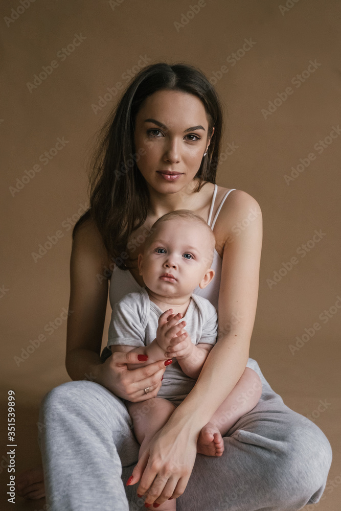 Beautiful portrait of mother and child in dark tones. Stylish prety brunet young woman with baby boy toddler playing smiling hug in studio. Love and tender feelings Beautiful portrait of mother and child in dark tones. Stylish prety brunet young woman with baby boy toddler playing smiling hug in studio. Love and tender feelings