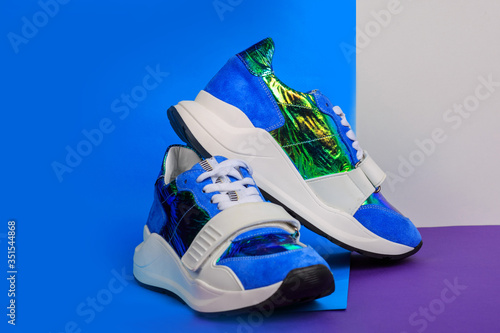 Blue sneakers on blue and pink background. Creative sport footwear design concept. Women or teenager glamorous shoes.