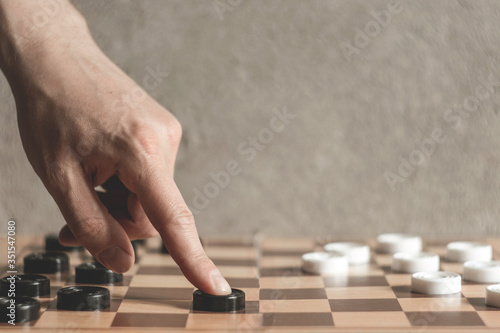 male hand moves a piece of checkers. black and white checkers. games for intelligence and strategy