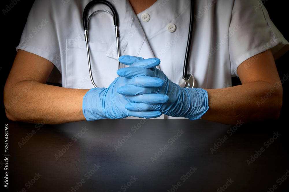 doctor with a stethoscope and blue gloves on a dark background doctor with a stethoscope and blue gloves on a dark background