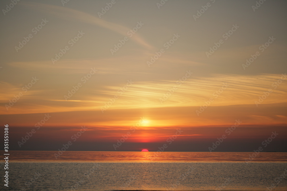Dramatic sunset at sea. The sun set halfway over the horizon
