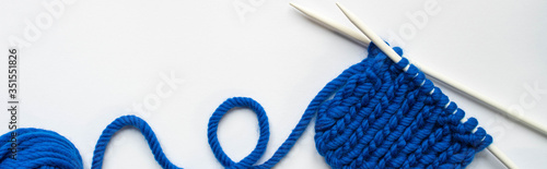 top view of blue wool yarn and knitting needles on white background, panoramic orientation