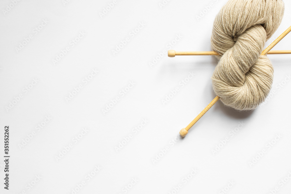 top view of beige wool yarn and knitting needles on white background top view of beige wool yarn and knitting needles on white background