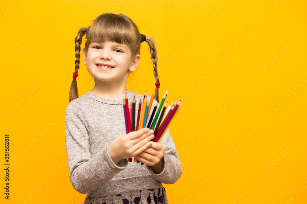 Portrait of happy lovely child girl drawing with colorful pencils isolated over yellow Portrait of happy lovely child girl drawing with colorful pencils isolated over yellow