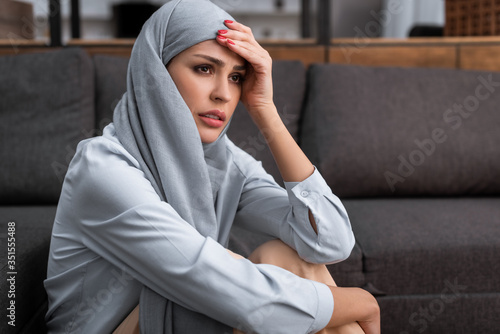 Canvas Print upset arabian woman in hijab touching forehead, domestic violence concept