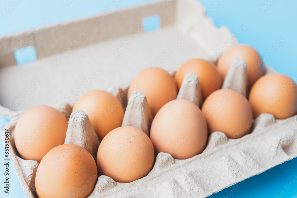 Close up chicken eggs in carton box on blue background. Close up chicken eggs in carton box on blue background.