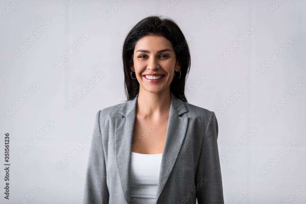 cheerful businesswoman smiling while looking at camera on white