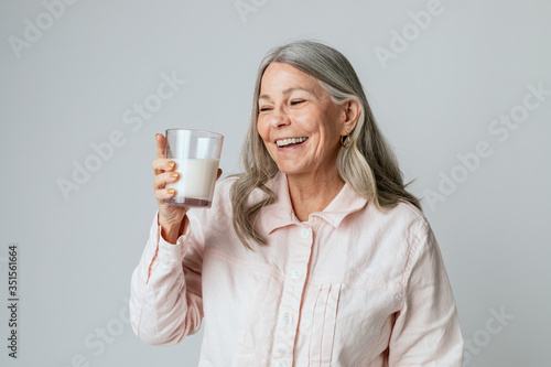 Cheerful senior woman drinking a glass of milk photo